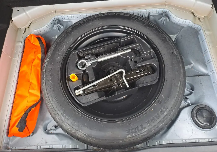 Vue plongeante sur la roue de secours noire et les outils dans le coffre d'une Citroën C4 Spacetourer blanc 2018.