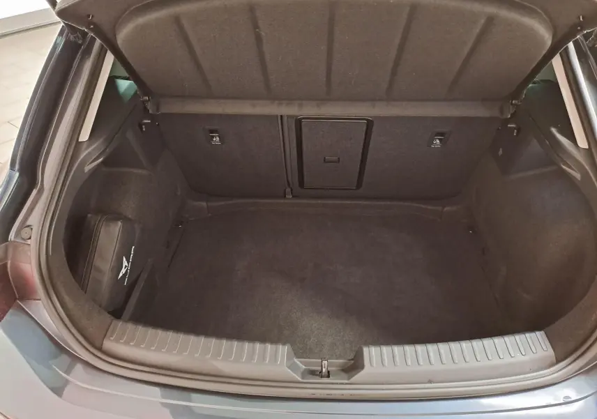 Coffre ouvert vu de l'arrière d'une CUPRA Leon gris magnétique, montrant un espace de rangement propre et vide.