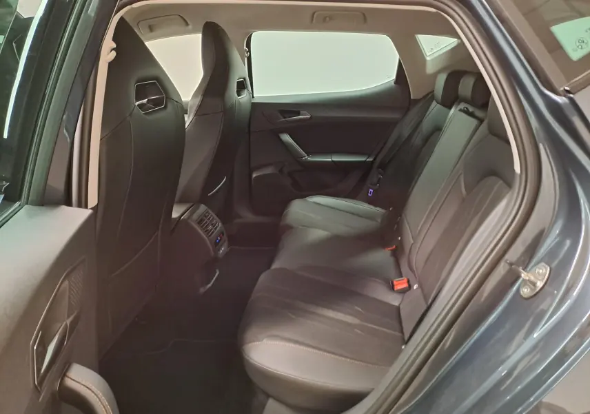 Vue intérieure arrière côté droit de la CUPRA Leon 1.5 TSI 150 DS7 gris magnétique, montrant les sièges arrière en cuir noir.