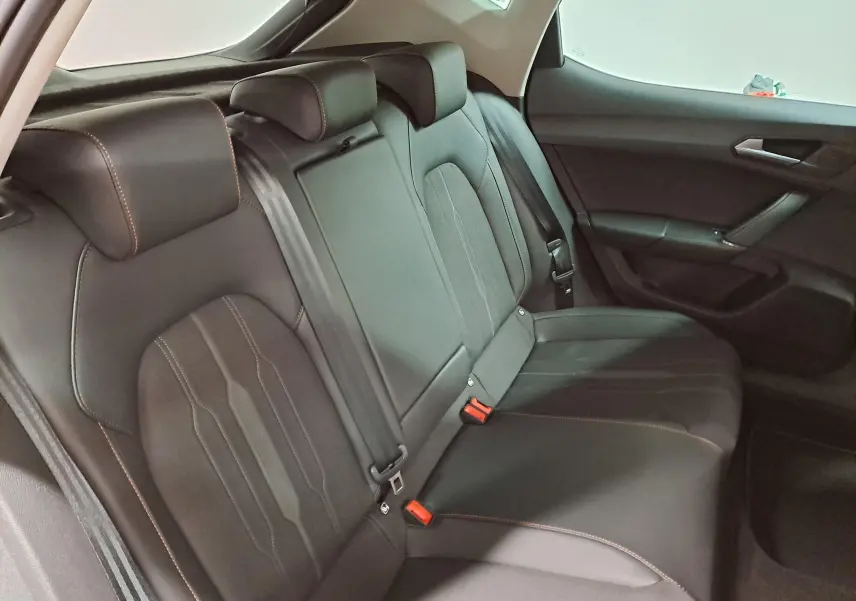 Vue intérieure côté droit des sièges arrière noirs avec surpiqûres orange d'une CUPRA Leon 1.5 TSI 2023 Gris Magnétique.