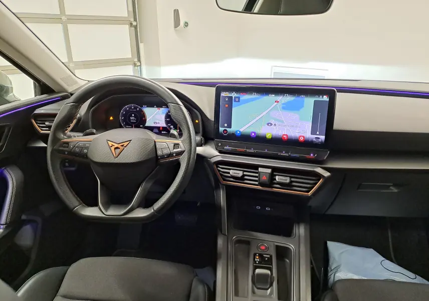 Vue intérieure du poste de conduite de la CUPRA Leon 1.5 TSI 150 DS7 V 2023 avec écran tactile central et volant multifonction.