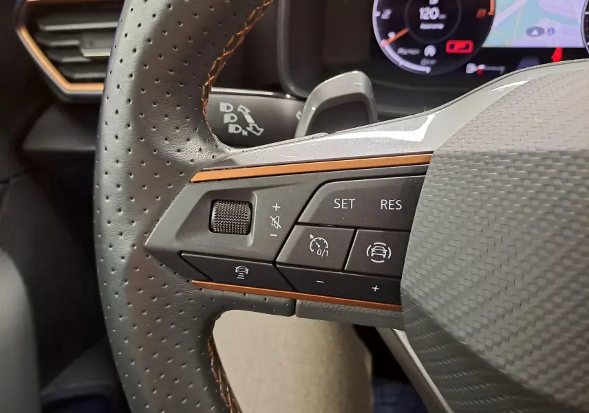 Gros plan sur le volant perforé avec commandes du régulateur adaptatif et finition carbone de la CUPRA Leon 2023.