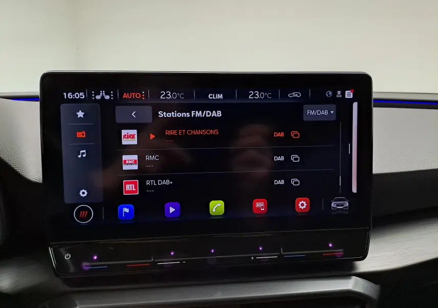 Écran tactile central de la CUPRA Leon 2023 affichant les stations FM/DAB avec interface moderne et commandes climatiques intégrées.