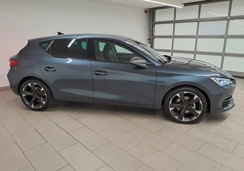 Vue de profil côté droit d'une CUPRA Leon 1.5 TSI 150 DS7 V gris magnétique avec jantes alliage distinctives.