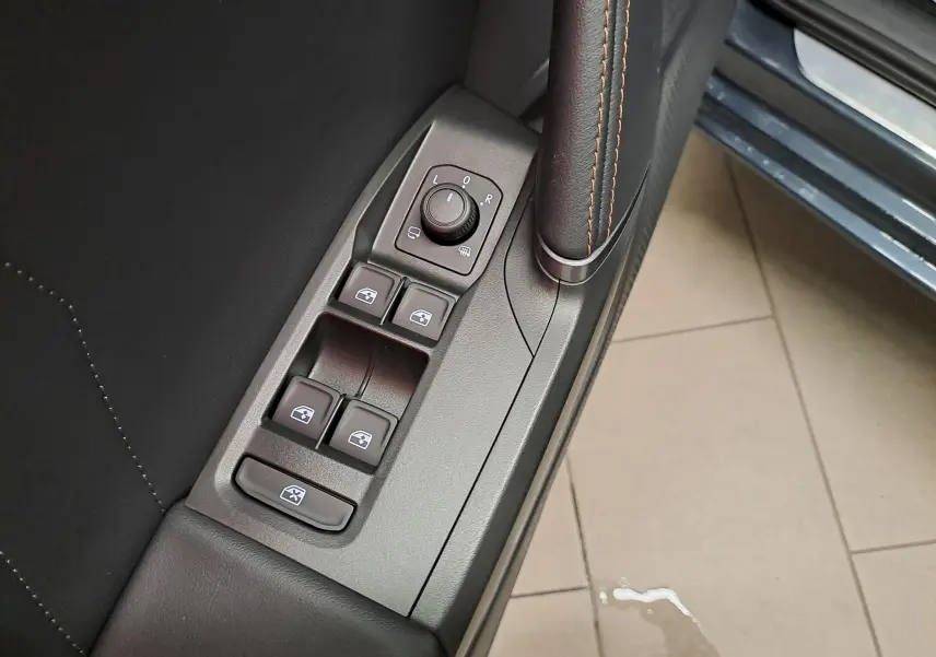 Gros plan sur les commandes des vitres et rétroviseurs côté gauche d’une CUPRA Leon gris magnétique 2023.