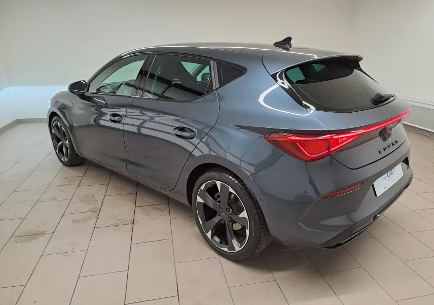 Vue 3/4 arrière droite d'une CUPRA Leon 1.5 TSI 150 DS7 gris magnétique avec feux arrière LED et jantes noires.