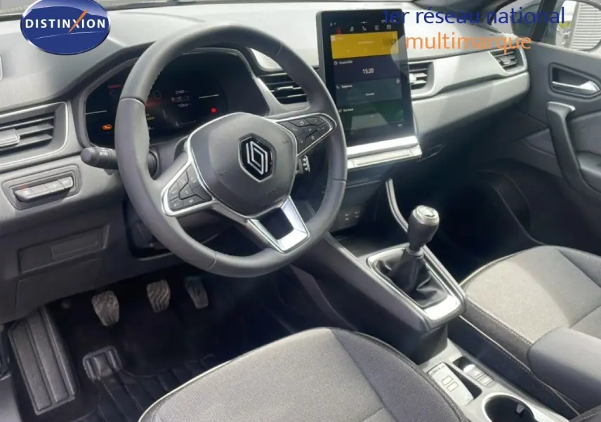 Vue intérieure côté conducteur du Renault Captur 2025, avec volant multifonction, écran tactile vertical et levier de vitesse manuel.