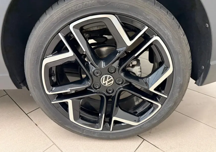 Gros plan sur la jante alliage noire et argentée 18 pouces avec logo Volkswagen au centre, montée sur pneu Hankook.