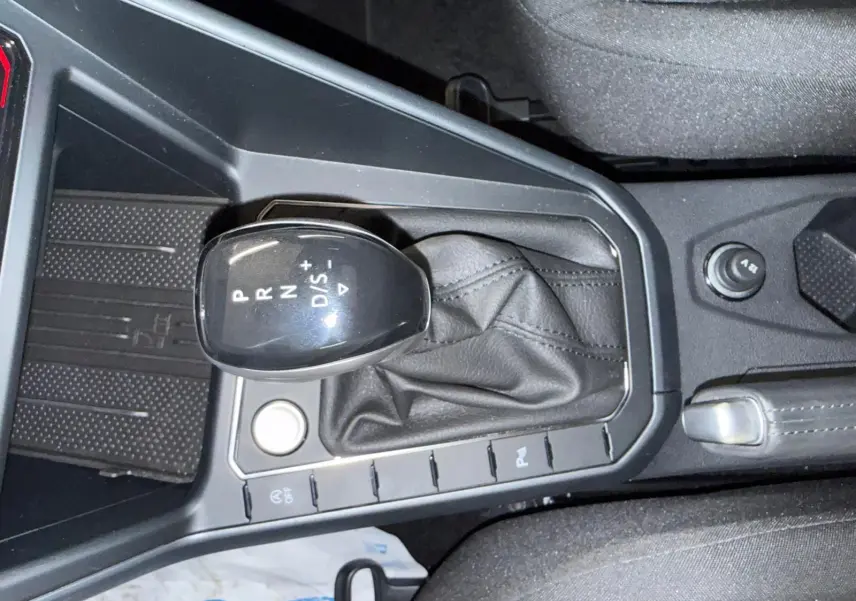 Gros plan sur le levier de vitesses automatique noir avec soufflet cuir dans le Volkswagen Taigo blanc toit noir.
