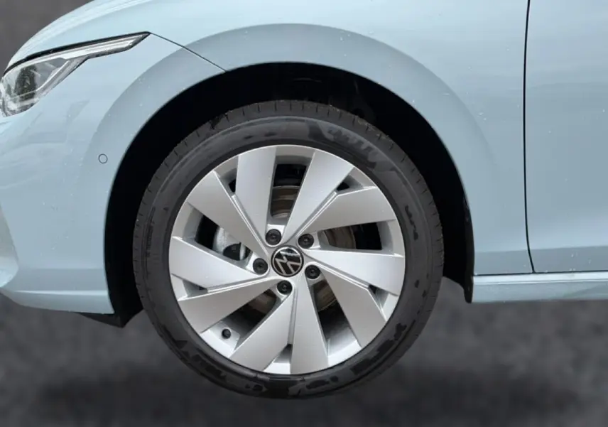 Gros plan sur la roue avant gauche et une partie de la carrosserie bleu glacier d'une Volkswagen Golf 2026.