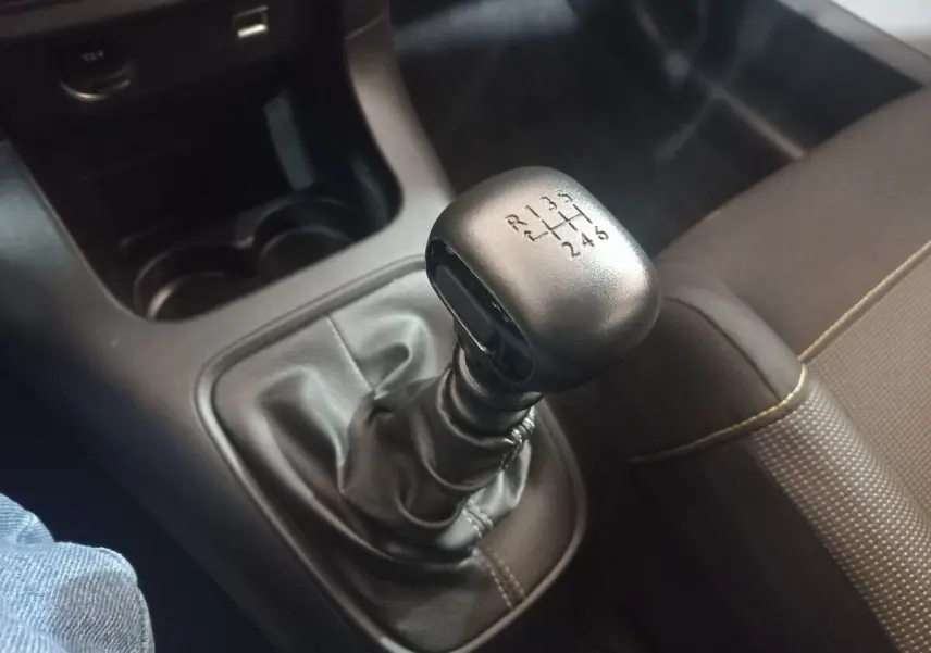 Gros plan sur le levier de vitesses manuel noir de la Citroën C3 2024, avec siège tissu marron à côté.