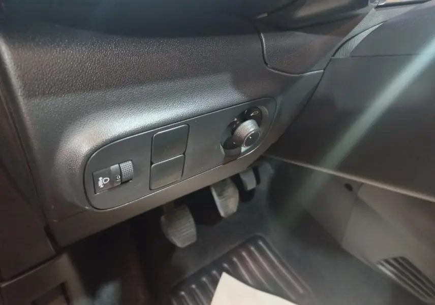 Détail du tableau de bord côté gauche noir avec commandes d’éclairage et pédales visibles dans une Citroën C3 2024.