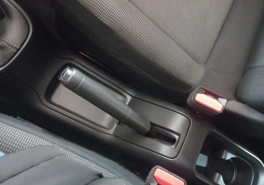 Vue rapprochée de la poignée de frein à main et des ceintures de sécurité noires à boutons rouges dans une Citroën C3 2024.