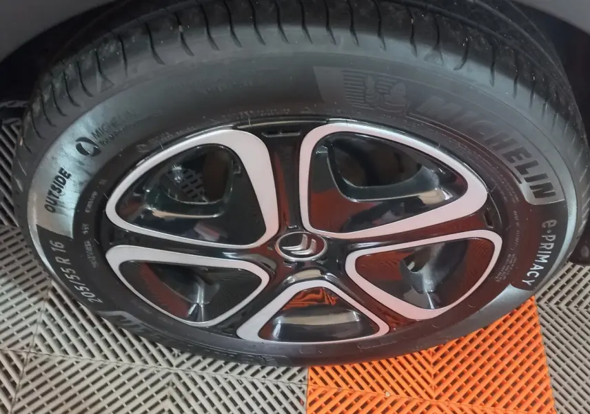 Gros plan sur la roue avant droite d’une Citroën C3 noire 2024 avec jante alliage bicolore et pneu Michelin.