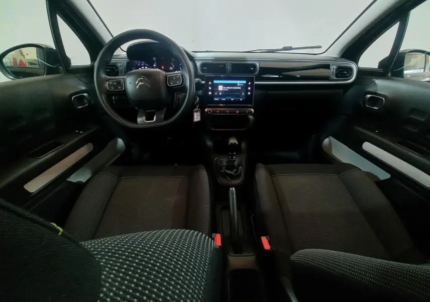 Vue intérieure avant de la Citroën C3 noire 2024, volant multifonctions, écran tactile central et boîte manuelle visible.