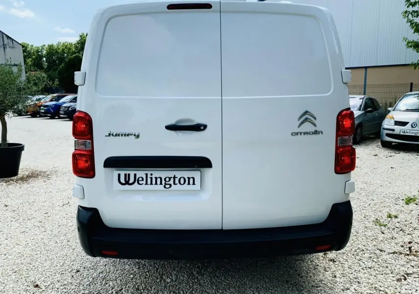 Vue arrière d'un utilitaire Citroën Jumpy blanc avec portes battantes et feux rouges visibles.