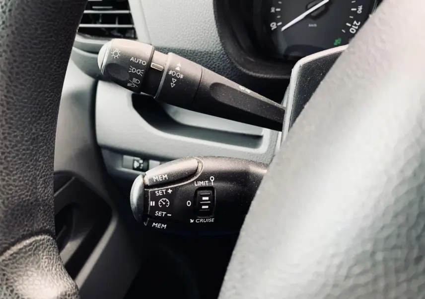 Gros plan sur les commandes au volant du Citroën Jumpy blanc 2020, mettant en valeur le régulateur de vitesse et les feux automatiques.