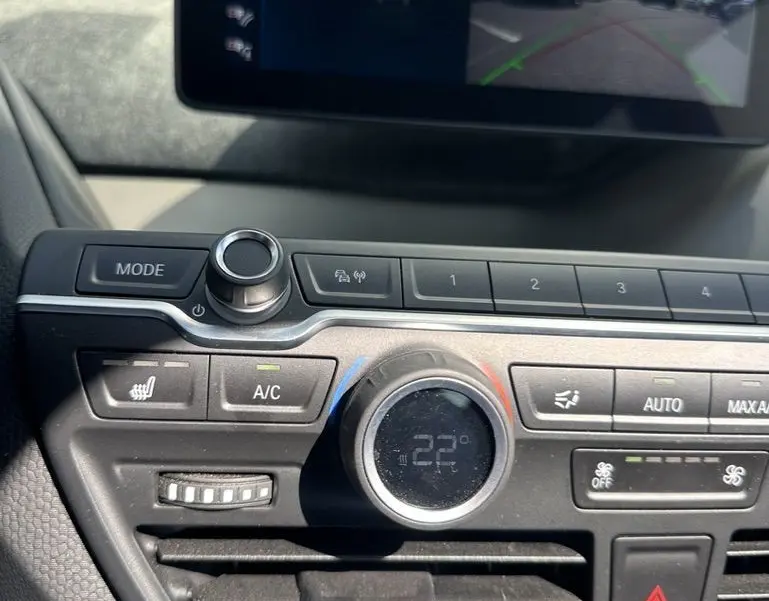Vue rapprochée du tableau de bord noir de la BMW i3 2022 avec écran multimédia et commandes de climatisation digitales.