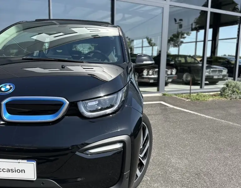 Vue 3/4 avant droite d'une BMW i3 noire électrique 2022, avec calandre bleue distinctive et phares LED modernes.