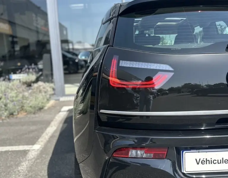 Vue arrière gauche d'une BMW i3 noire 2022, mettant en valeur les feux arrière LED distinctifs et la silhouette compacte électrique.