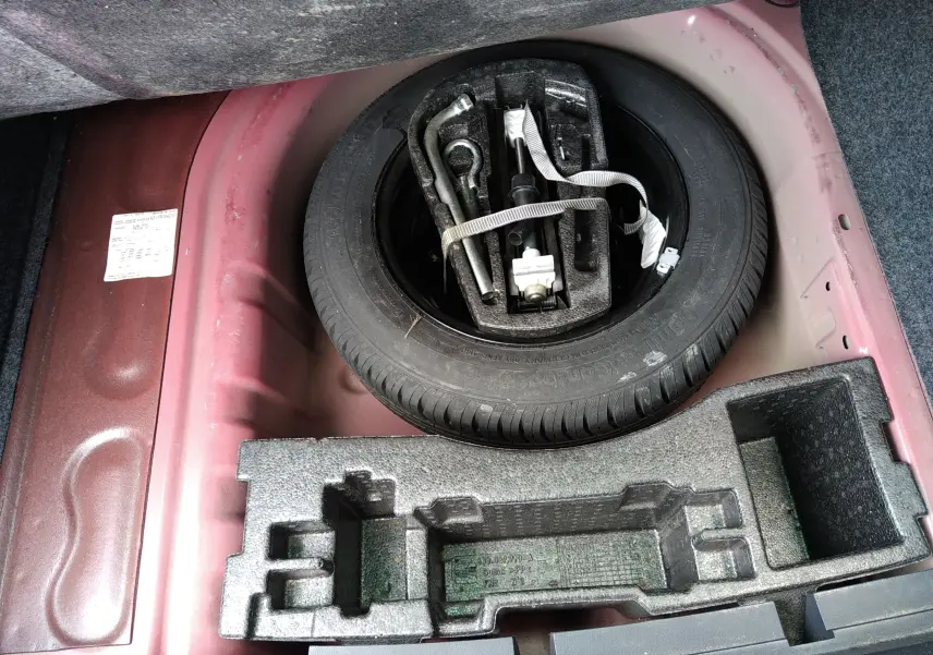 Vue rapprochée sur la roue de secours et les outils dans le coffre rouge d’une SEAT IBIZA ST 2015.