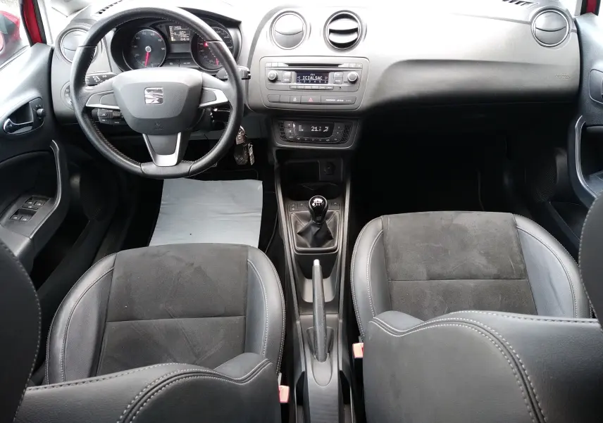 Vue intérieure avant de la SEAT Ibiza ST 1.2 TSI 2015, volant cuir, sièges alcantara noirs et boîte manuelle.