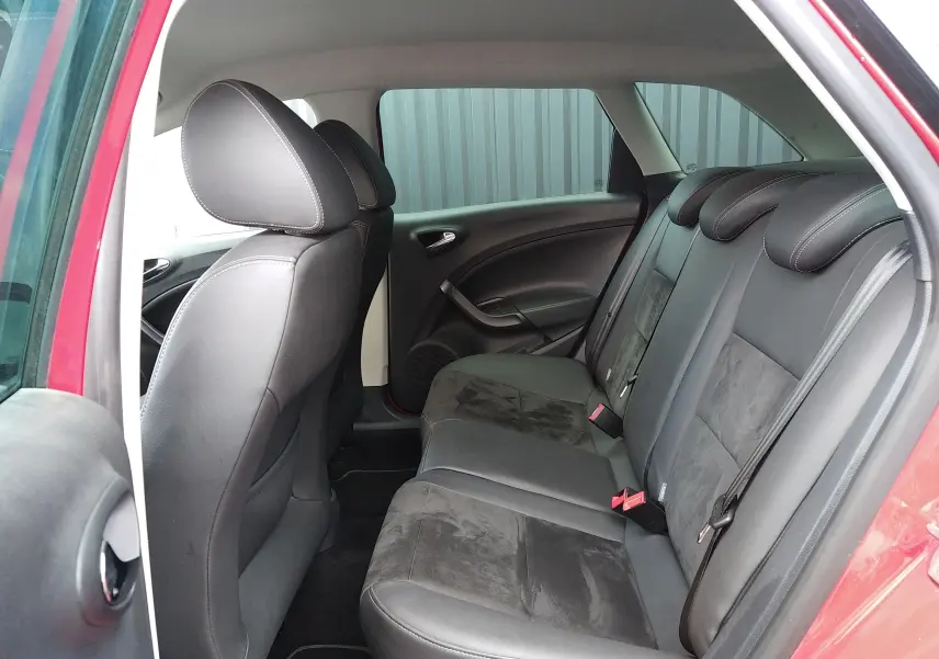 Vue intérieure arrière côté gauche de la SEAT Ibiza ST rouge, montrant les sièges arrière en cuir et alcantara noirs.