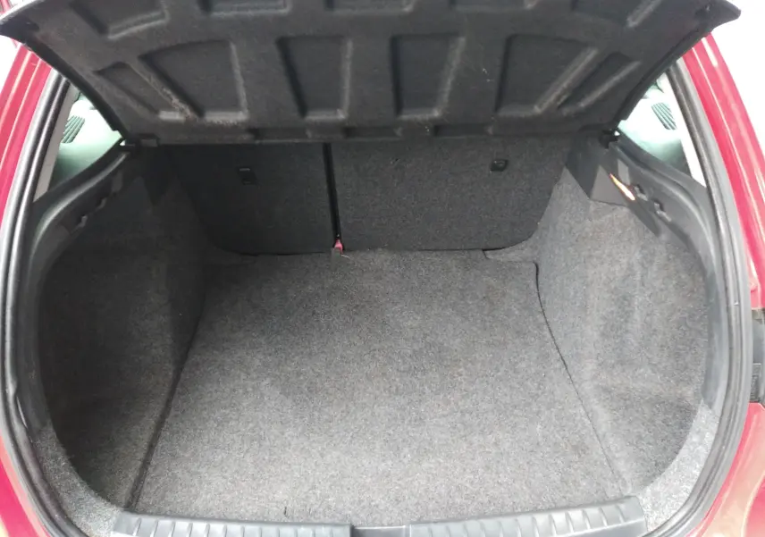 Coffre ouvert vu de l'arrière d'une SEAT Ibiza ST rouge de 2015, montrant un espace de chargement vide et propre.