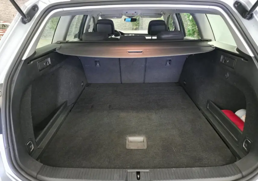Coffre spacieux ouvert d'une Volkswagen Passat SW gris, avec cache-bagages et banquette arrière visible.