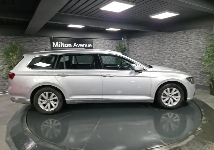 Volkswagen Passat SW gris métallisé vue de profil côté gauche dans un showroom intérieur moderne.