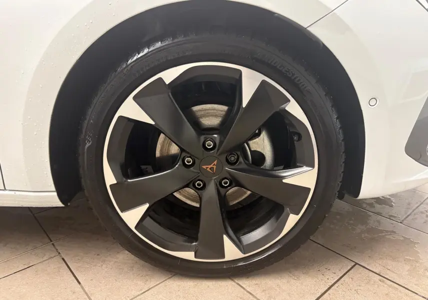 Gros plan sur la roue avant gauche de la CUPRA Leon blanche Nevada avec jante noire et argentée au design moderne.