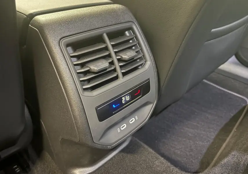 Détail de la console arrière avec commandes de climatisation et ports USB dans l'habitacle noir du CUPRA Leon 2024.