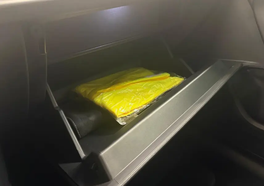 Gant de sécurité jaune dans la boîte à gants ouverte côté passager d'une CUPRA Leon 2024 blanc Nevada.