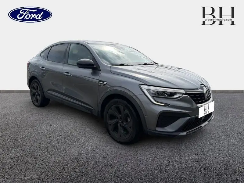 Renault Arkana gris métallisé en vue 3/4 avant droit, avec jantes noires et signature lumineuse LED distinctive.