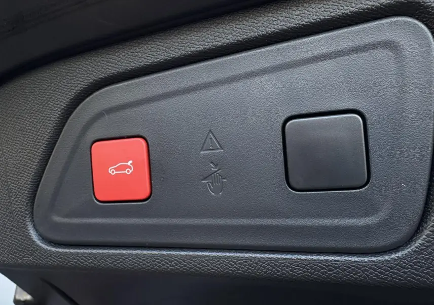 Gros plan sur les boutons du hayon électrique du Citroën C5 Aircross noir, avec bouton rouge d'ouverture et bouton noir carré.