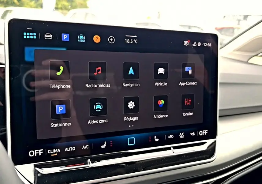 Écran tactile central affichant les options multimédias et de navigation dans une Volkswagen Golf noire, vue intérieure côté passager.