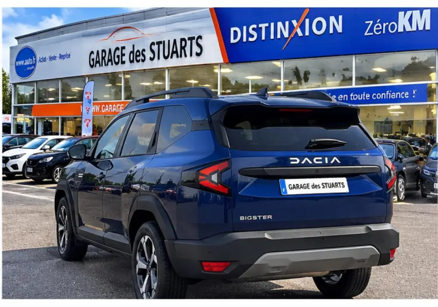 Vue 3/4 arrière droite du Dacia Bigster 2026 bleu indigo avec logo et plaque Garage des Stuarts visible.
