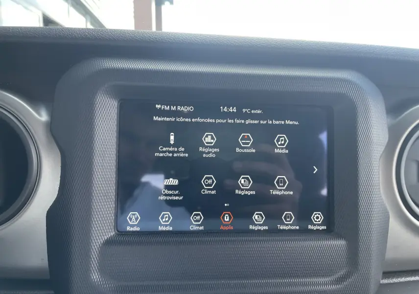 Écran tactile central du tableau de bord de la Jeep Wrangler blanc 2018, affichant les options multimédia et réglages.