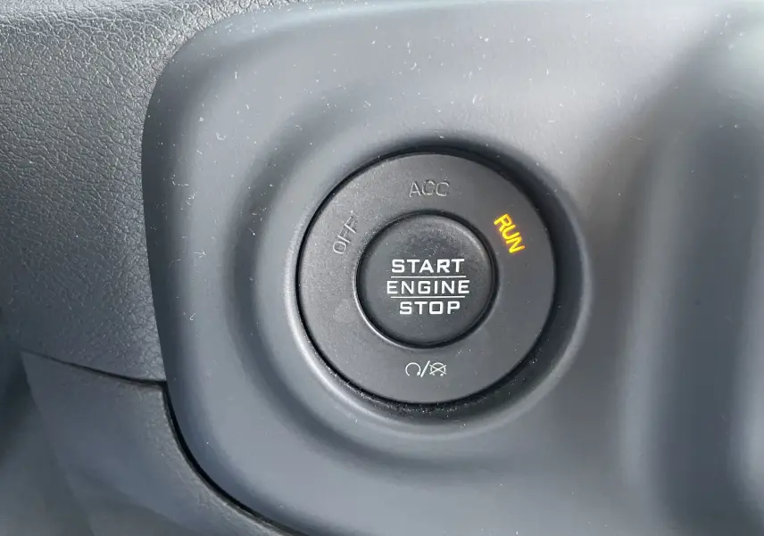 Bouton de démarrage moteur noir avec indication RUN allumée sur le tableau de bord d'une Jeep Wrangler blanche 2018.