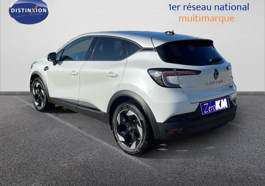 Vue 3/4 arrière droite d'un Renault Captur blanc nacré avec toit gris, soulignant ses jantes noires et son design moderne.