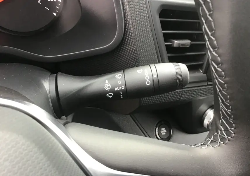Gros plan sur la commande des essuie-glaces à gauche du volant du Renault Trafic Fourgon noir, avec bouton start visible.