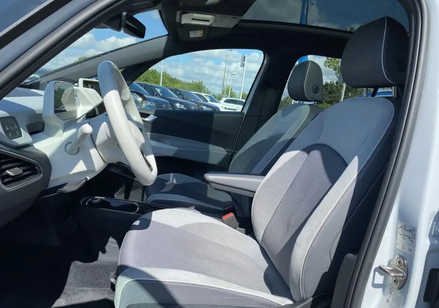 Intérieur avant droit d'une Volkswagen ID.3 blanc glacier, sièges tissu velours gris et toit vitré panoramique visible.