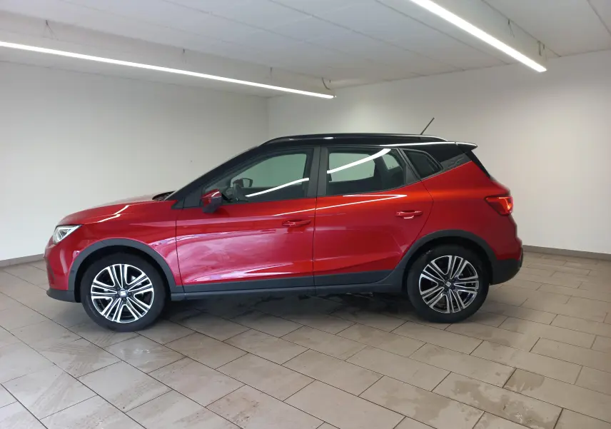 Vue de profil côté gauche d'un SEAT Arona 2025 rouge Désir avec toit noir Minuit et jantes alliage.