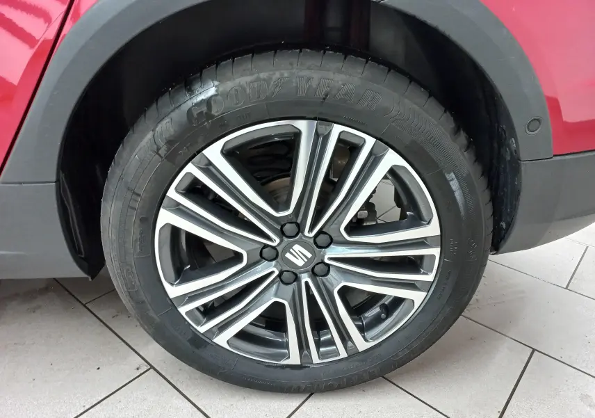 Gros plan sur la roue avant droite du SEAT Arona rouge Désir avec jante alliage bicolore et pneu Goodyear.