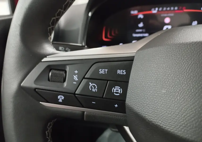 Gros plan sur les commandes au volant côté gauche du SEAT Arona 2025, boutons du régulateur de vitesse adaptatif et assistant de conduite.