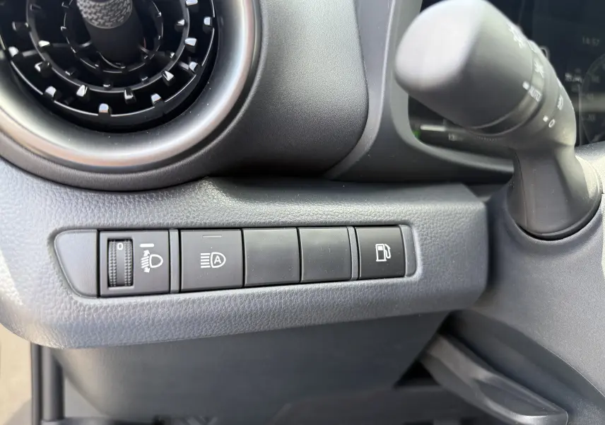 Gros plan sur les commandes à gauche du volant du Toyota C-HR 1.8 Hybride 140 Style 2025, tableau de bord gris.