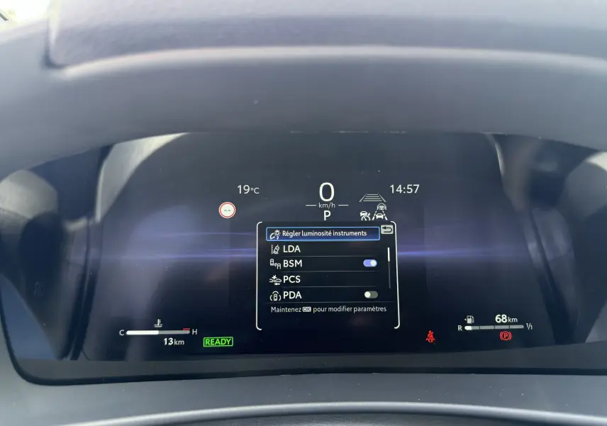 Affichage numérique du tableau de bord du Toyota C-HR 1.8 Hybride 2025 avec menu réglage luminosité et indicateurs actifs.