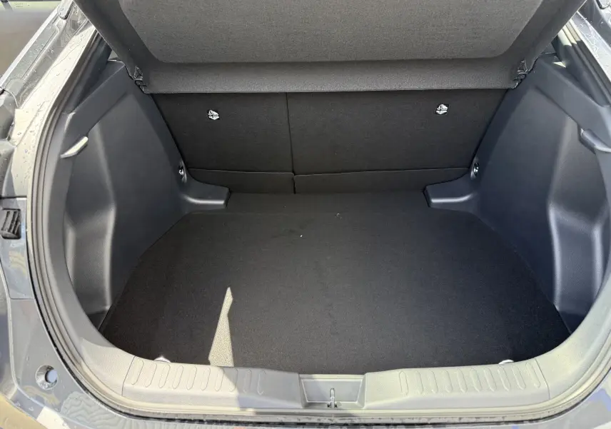 Coffre ouvert vu de l'arrière d'un Toyota C-HR 1.8 Hybride 140 Style gris atlas, espace de chargement vide et propre.