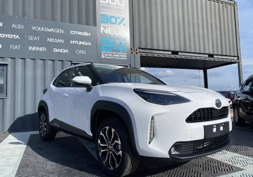 Toyota Yaris Cross blanc pur vue 3/4 avant droit avec jantes alliage et rétroviseurs blancs sur fond urbain.