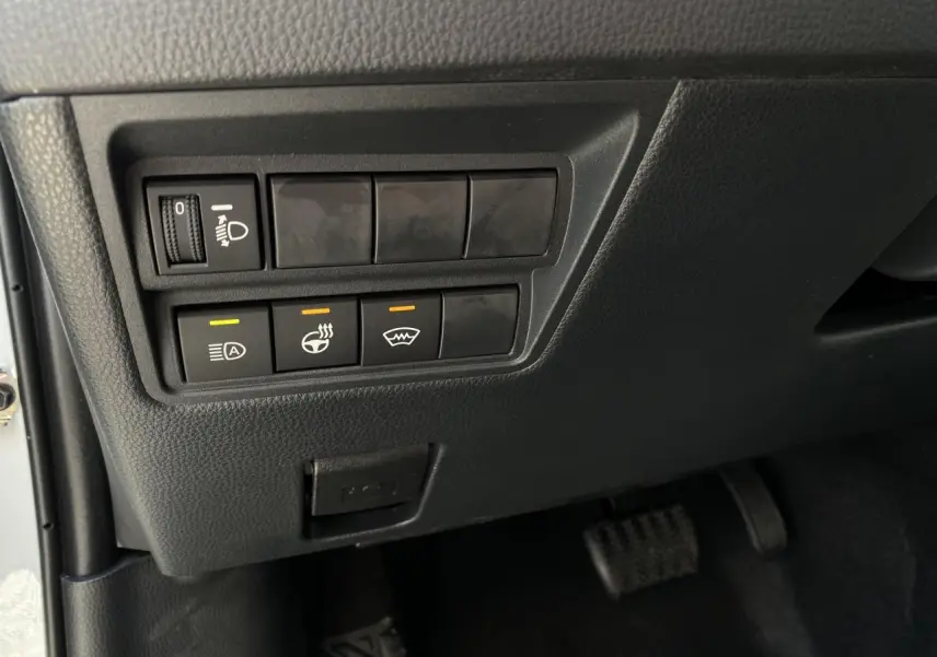 Gros plan sur les commandes sous le tableau de bord côté gauche du Toyota Yaris Cross blanc 2025 hybride.